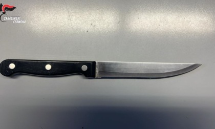 Lancia bottiglie a terra e minaccia i passanti con un coltello da cucina
