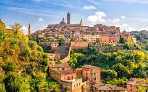 Giornata serena a Siena, nubi residue sui rilievi toscani